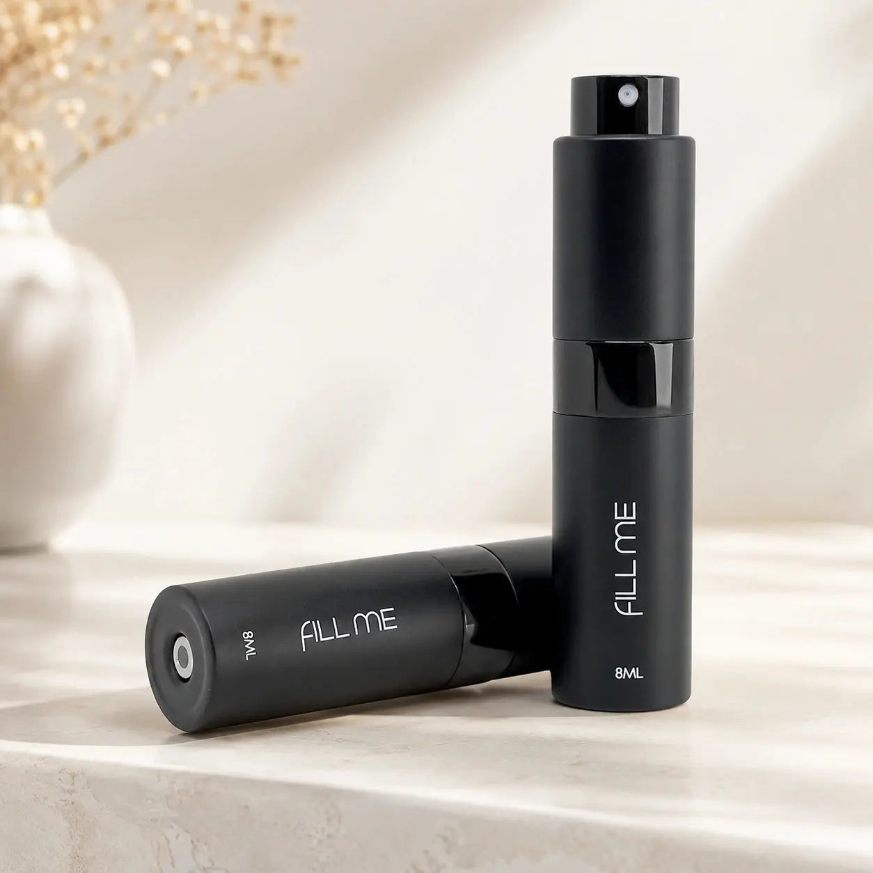 Fill Me refillable 8ml travel perfume atomiser bottle black hero image showing two matte black atomisers in a premium neutral setting.