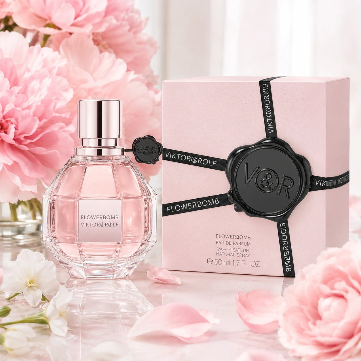 Viktor & Rolf Flowerbomb 50ml EDP women's perfume hero image with the original faceted pink bottle and box styled with soft pink peonies and petals.