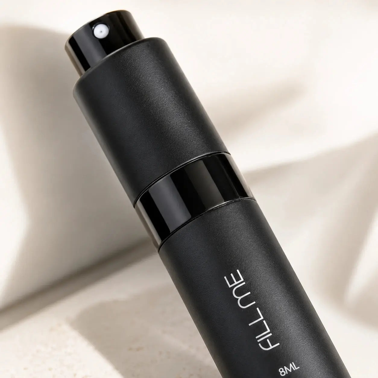 Fill Me refillable 8ml travel perfume atomiser bottle black close-up detail image highlighting the matte texture, spray nozzle, and glossy centre band.
