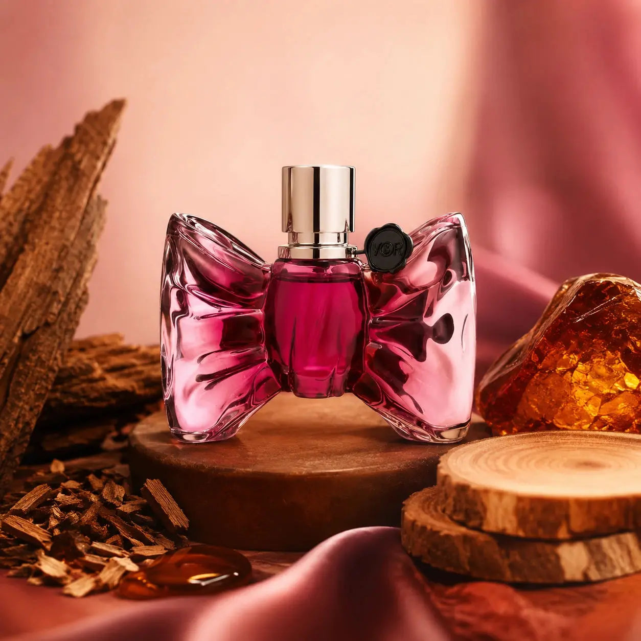 Viktor & Rolf Bonbon EDP 90ml base notes image with cedar, guaiac wood, sandalwood and amber styled around the original Bonbon perfume bottle in a warm sensual setting.