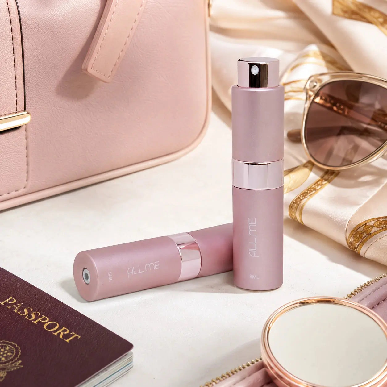 Fill Me refillable 8ml travel perfume atomiser bottle pink lifestyle image styled with travel essentials including handbag, sunglasses, passport and mirror.