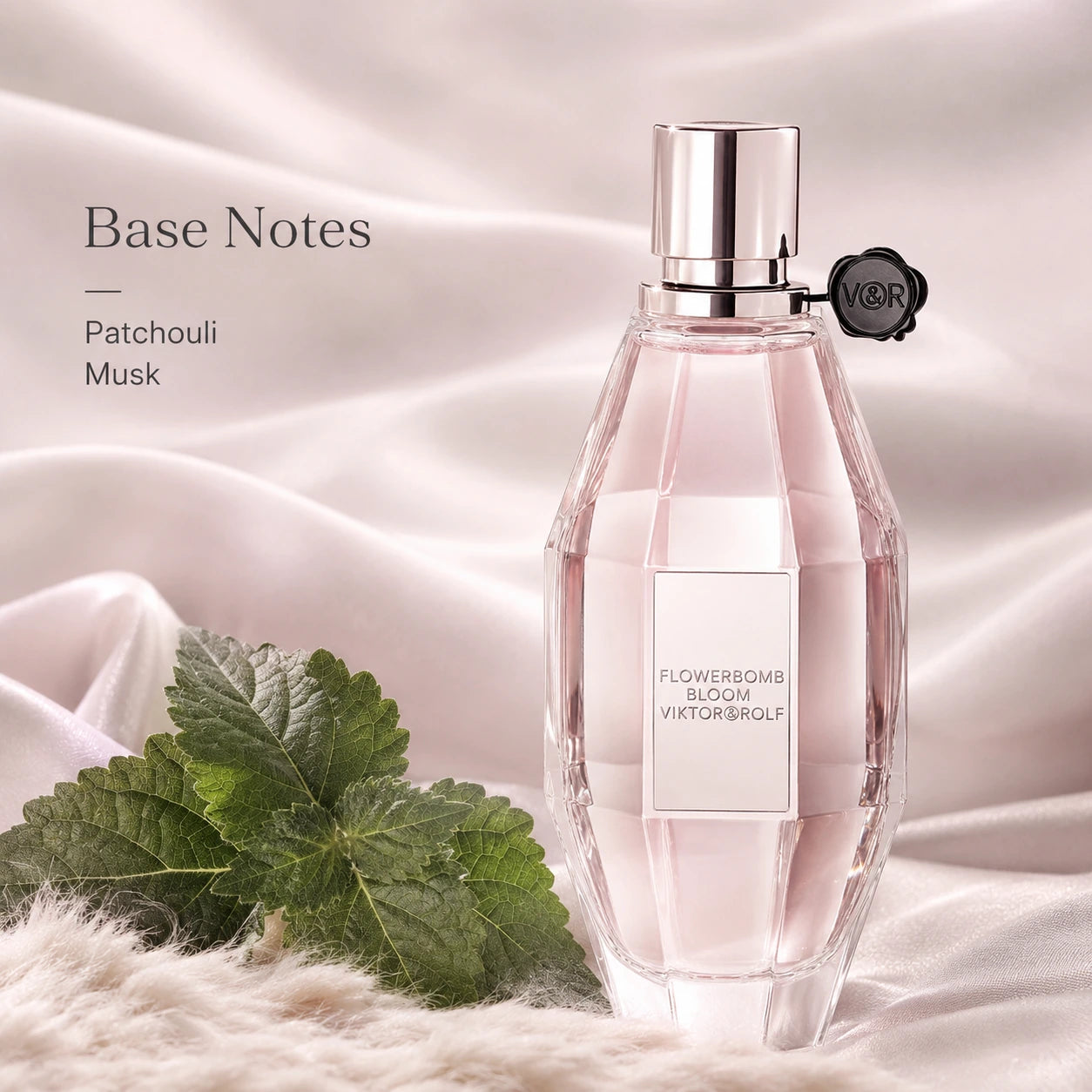 Viktor & Rolf Flowerbomb Bloom perfume bottle with green leaves on a soft fabric background