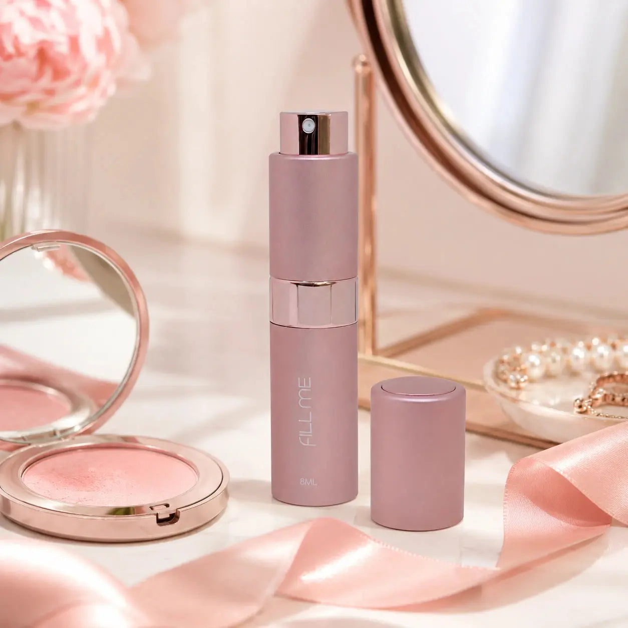 Fill Me refillable 8ml travel perfume atomiser bottle pink vanity lifestyle image styled with blush makeup, mirror, pearls and ribbon.