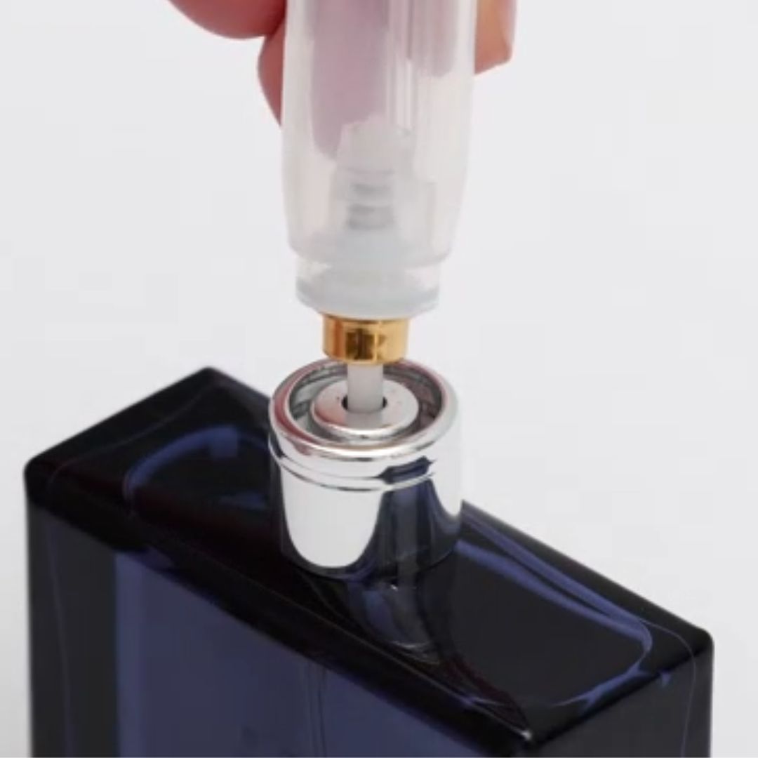 Close-up of a perfume bottle cap being removed by a hand on a white background