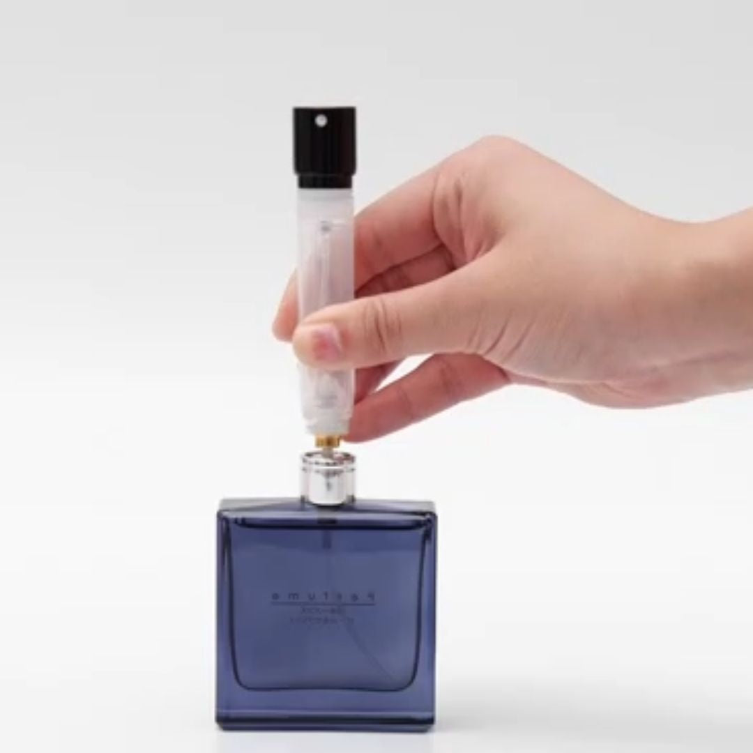 Hand holding a blue perfume bottle with a dropper on a white background