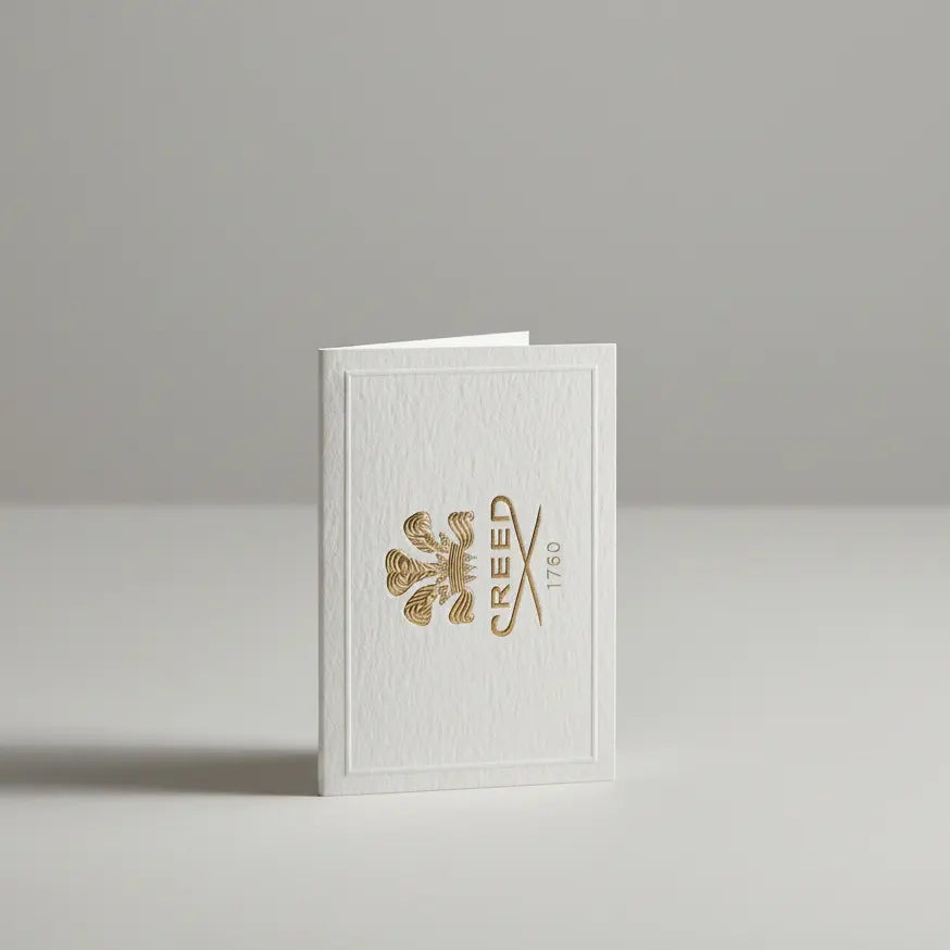 Creed perfume bottles and a branded box on a marble surface with a blurred background of more bottles.
