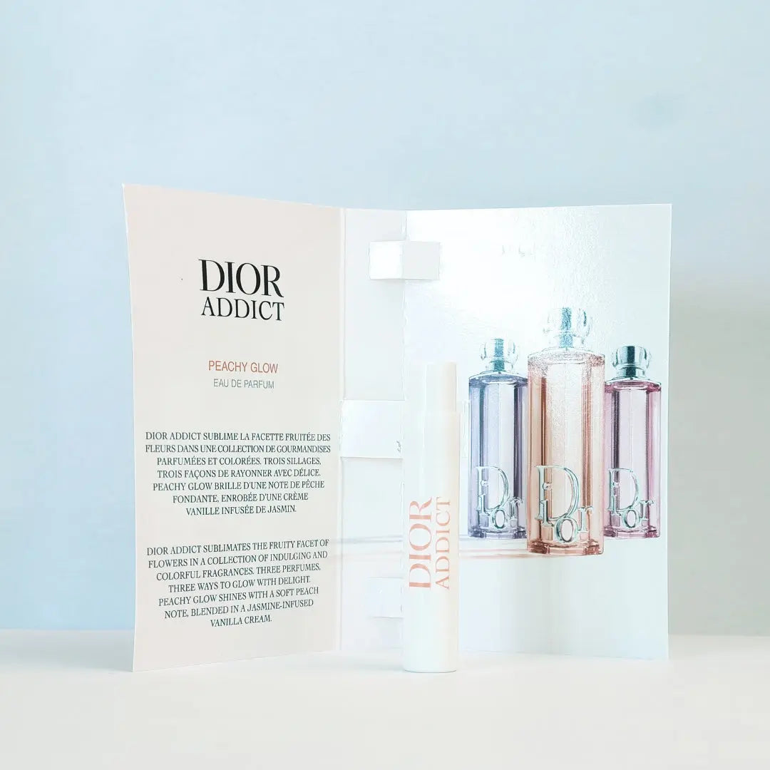 Dior Addict peach glow perfume packaging with three bottles on a light blue background