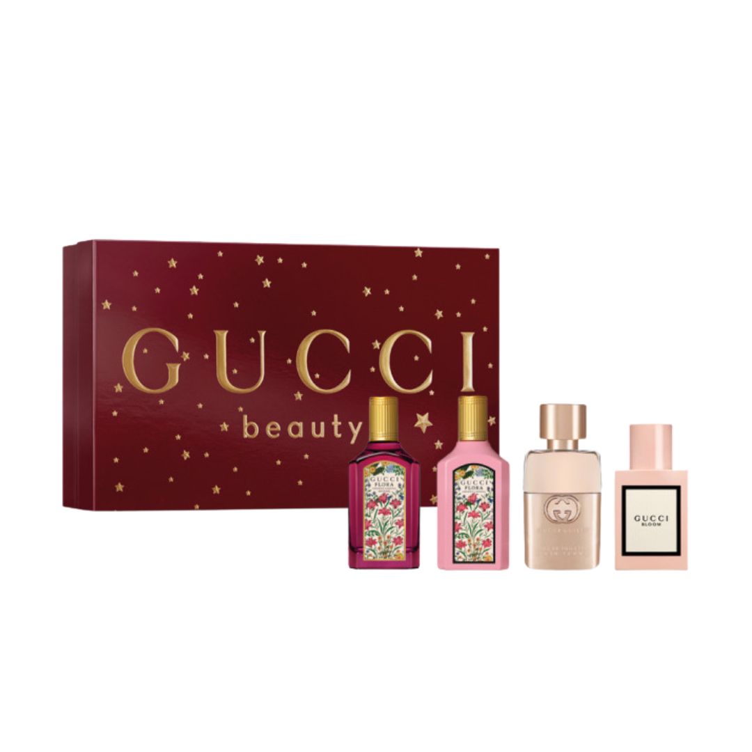 Gucci Mini Discovery 4pc Gift Set, a vibrant floral and gold box containing four 5ml miniature bottles (Gucci Guilty, Bloom, Flora Gardenia, Flora Gardenia Intense), suggesting a diverse wardrobe of modern floral scents.