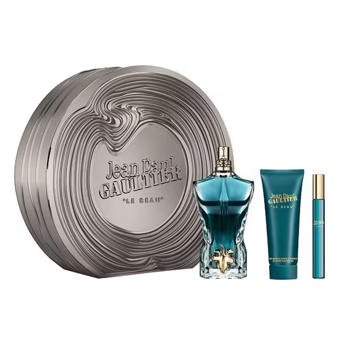 Jean Paul Gaultier Le Beau EDT 125ml 3pc Gift Set featuring metal box alongside a gold-neckled perfume bottle, a white body wash tube, and a small travel spray bottle on a white background.