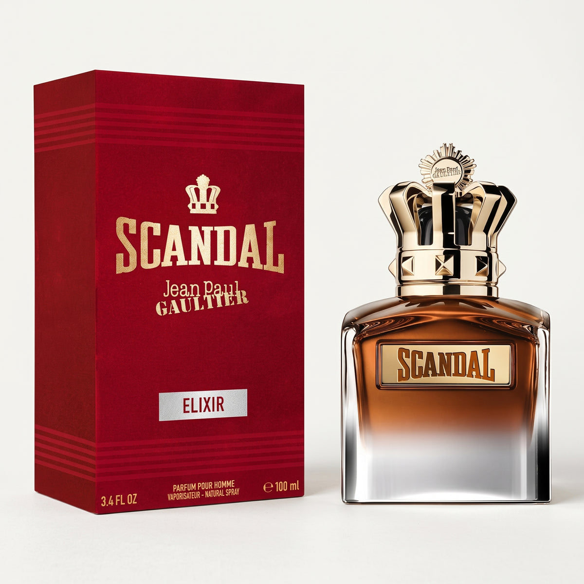 Jean Paul Gaultier Scandal Elixir perfume bottle with a metallic gold crown cap next to its deep red packaging box, set against a clean off-white background.