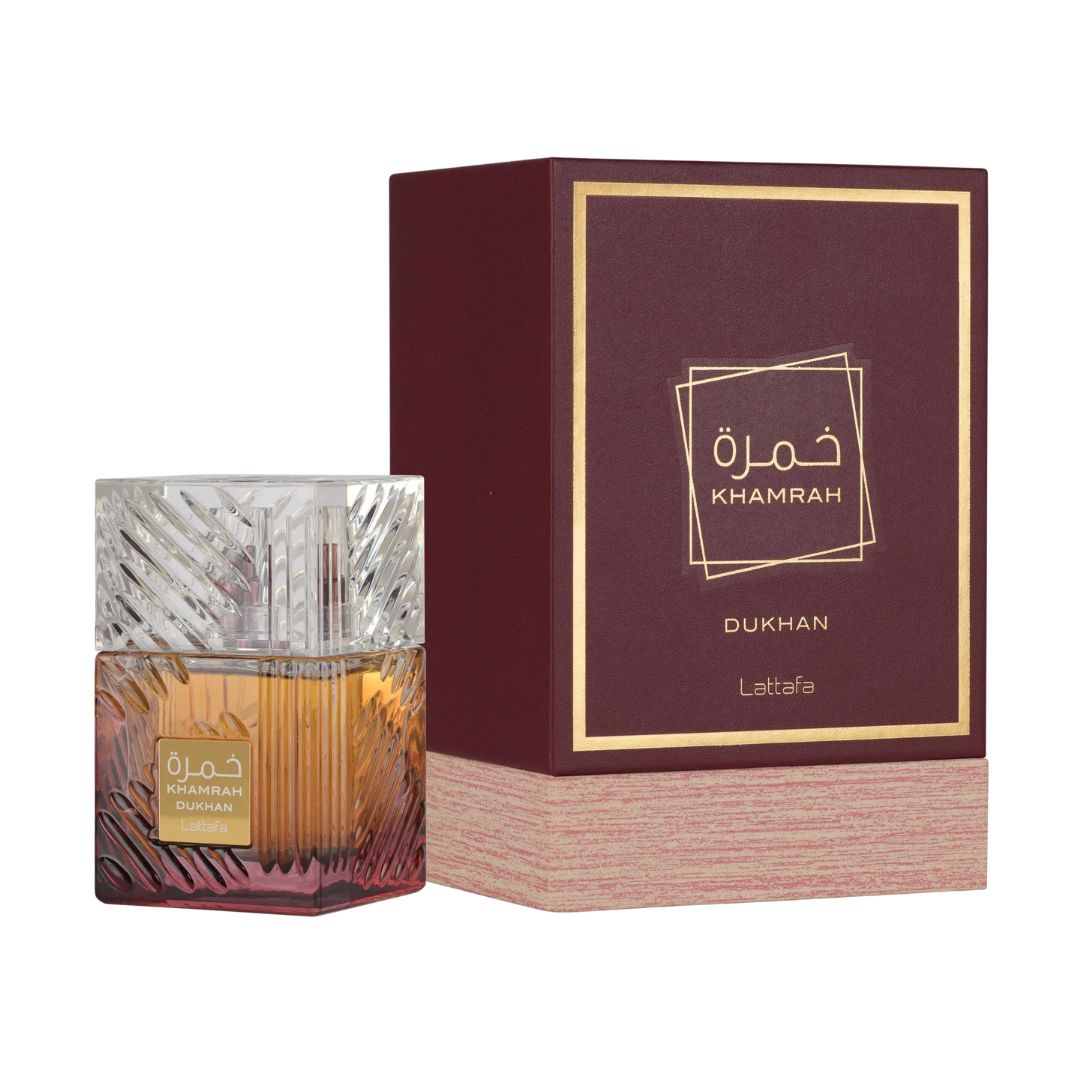 Lattafa Khamrah Dukhan EDP 100ml, an opulent, ornate clear bottle with gold detailing, showcasing a dark amber liquid and suggesting a rich, smoky oriental scent with tobacco and praline notes.