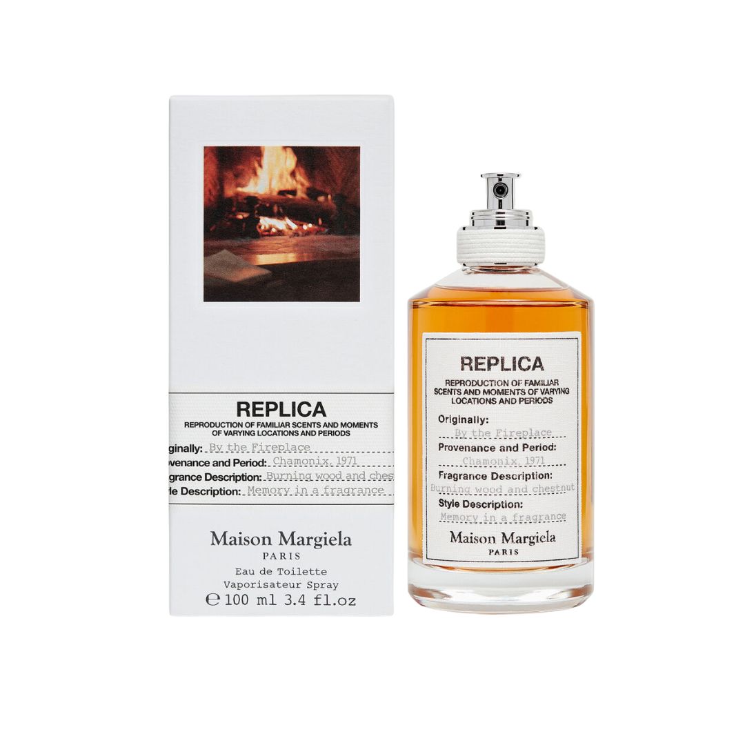 Maison Margiela Replica By The Fireplace 100ml EDT, a clear bottle with a warm, smoky amber liquid, evoking the comforting scent of a crackling fireplace and roasted chestnuts.