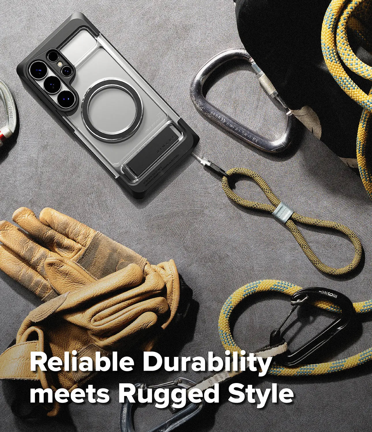 Phone case with ring holder, gloves, carabiners, and lanyard on a gray surface with text 'Reliable Durability meets Rugged Style'.