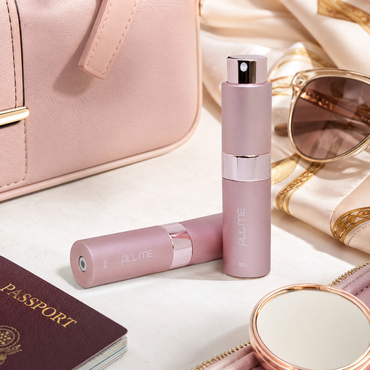 Fill Me refillable 8ml travel perfume atomiser bottle pink lifestyle image styled with travel essentials including handbag, sunglasses, passport and mirror.
