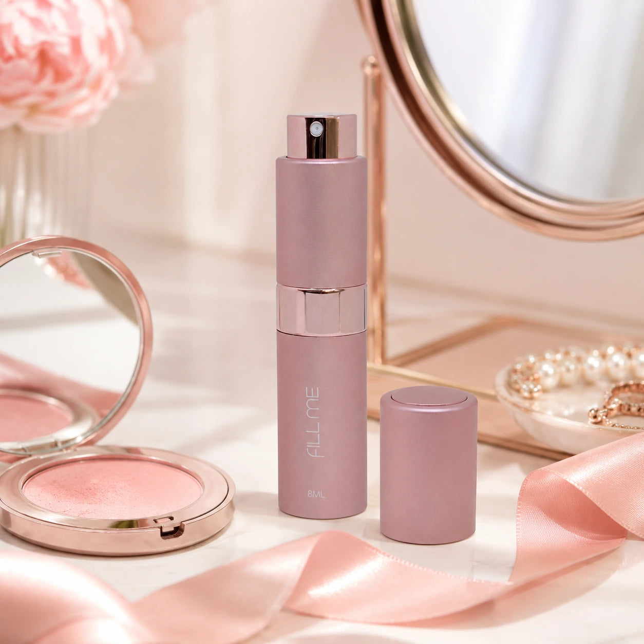 Fill Me refillable 8ml travel perfume atomiser bottle pink vanity lifestyle image styled with blush makeup, mirror, pearls and ribbon.