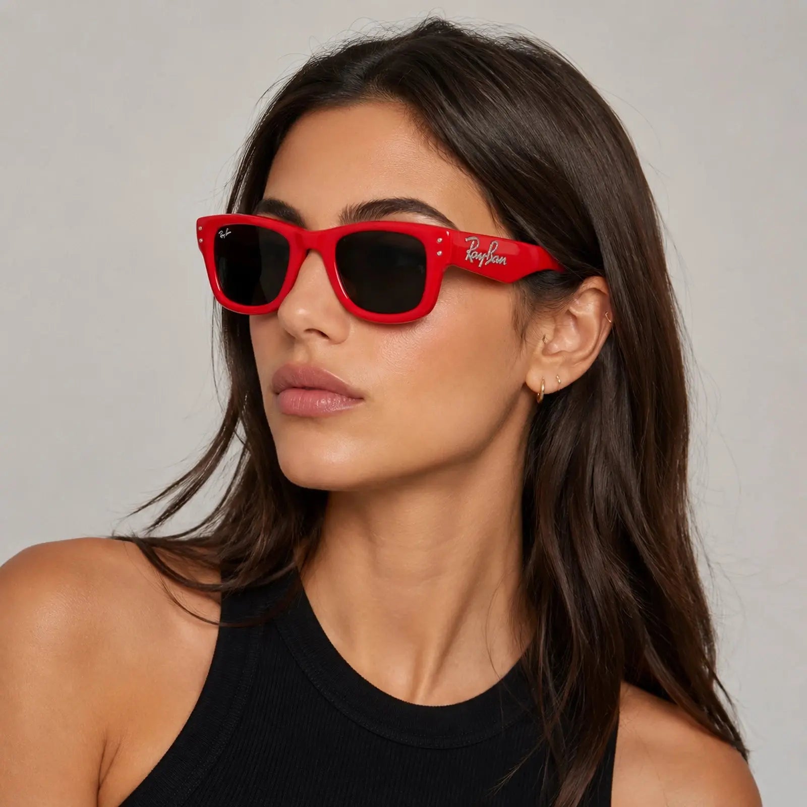 Woman wearing red sunglasses with a neutral background