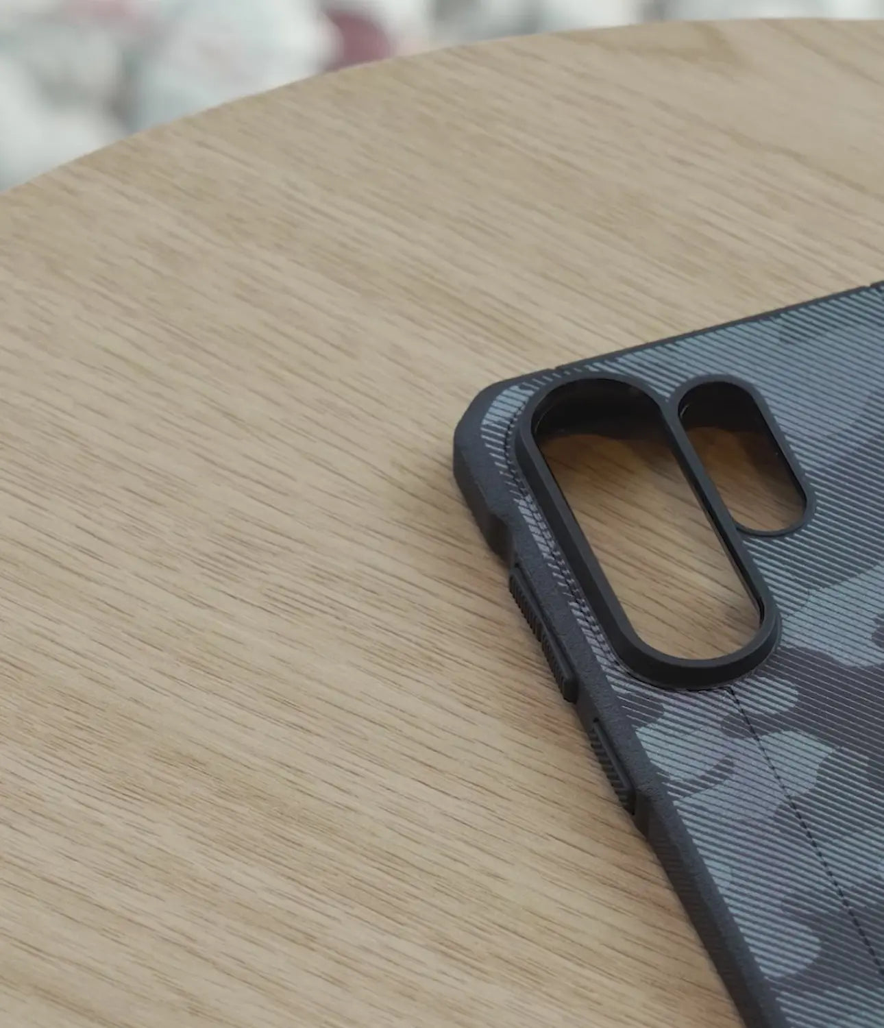 Phone case with a camouflage pattern on a wooden surface