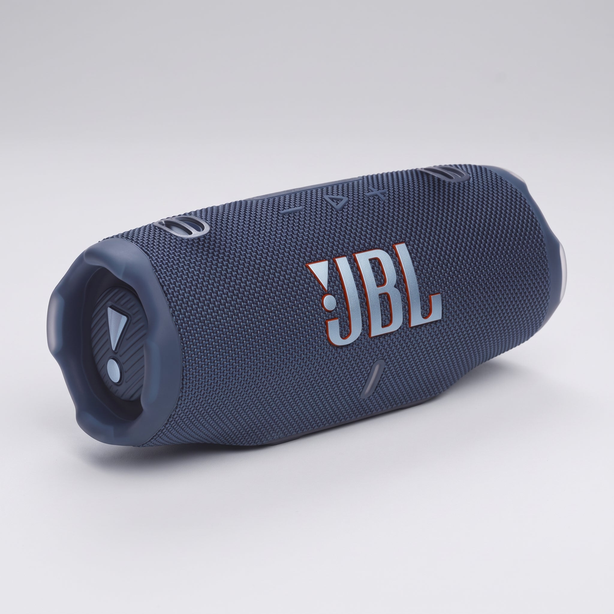 JBL Charge 6 Portable Bluetooth Speaker with Powerbank Auracast - Blue with a textured fabric cover and a prominent white and orange JBL logo on the side, shown on a light gray studio background.