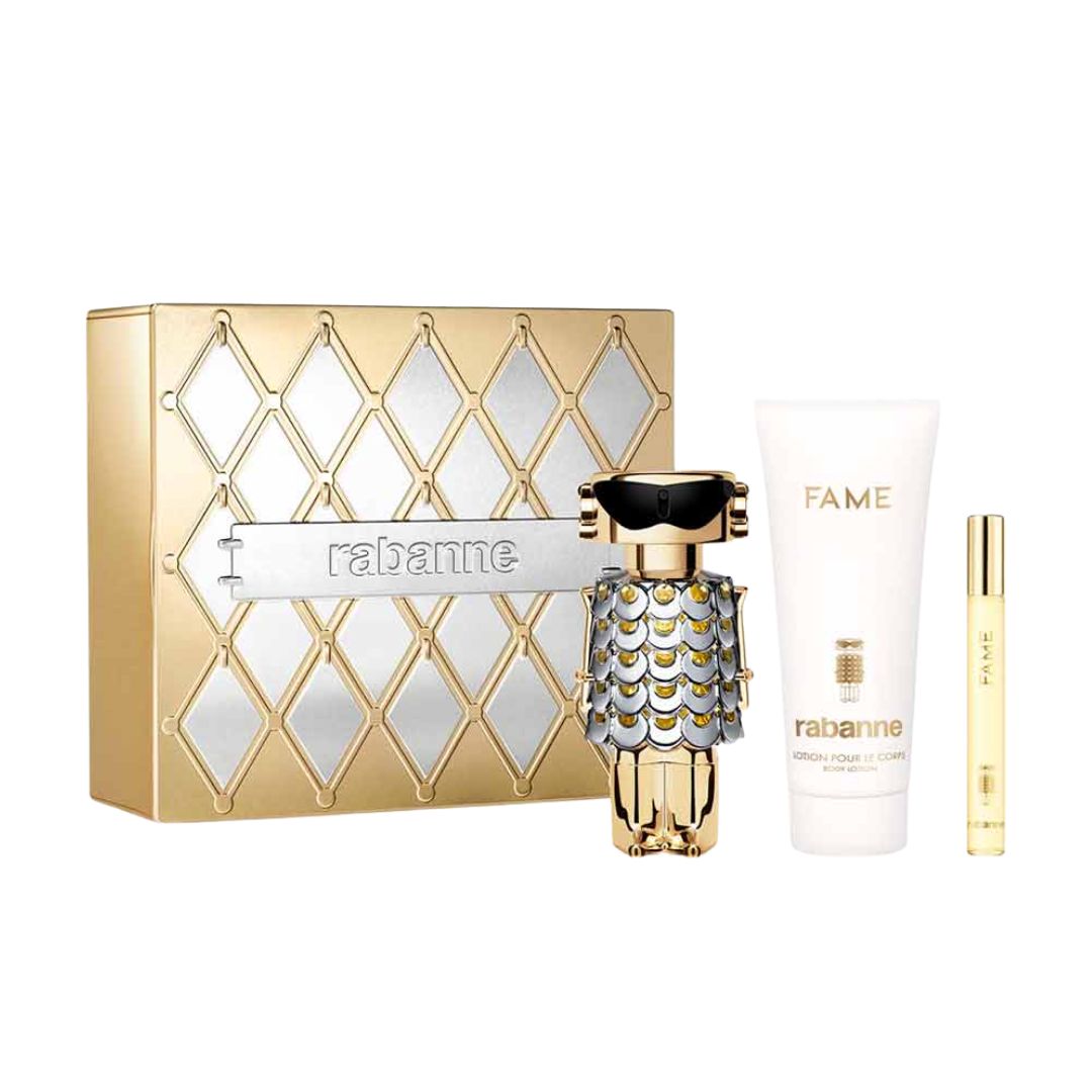 Rabanne Fame 3pc Gift Set, a vibrant white and gold box containing an 80ml EDP, 100ml Body Lotion, and 10ml Travel Spray, featuring the iconic robot bottle design and suggesting a fruity-floral amber scent.