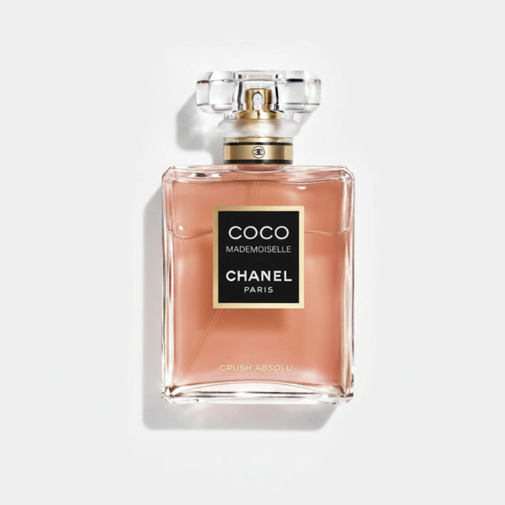 Chanel Coco Mademoiselle 100ml perfume bottle in a peach-pink shade, featuring the classic black label with gold trim and a clear faceted cap, set against a light gray background.