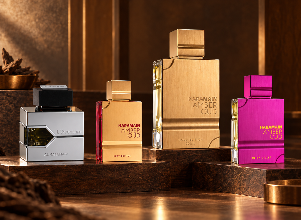Al Haramain L’Aventure, Amber Oud Ruby, Gold Edition and Ultra Violet bottles on dark walnut with warm amber light.