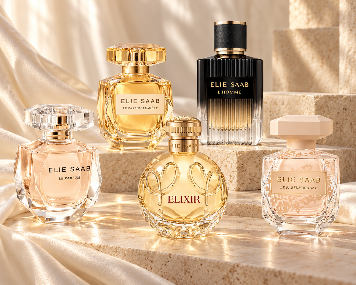 Five Elie Saab bottles—Le Parfum, Bridal, Elixir, Lumière and L’Homme—among ivory silk and pale stone.