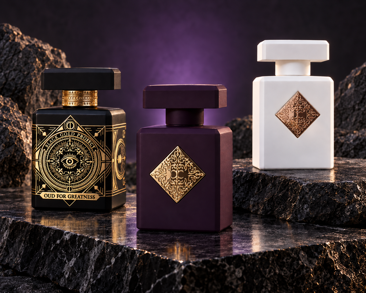 Initio Oud for Greatness, Psychedelic Love and Paragon bottles in a charcoal mineral setting with violet light.