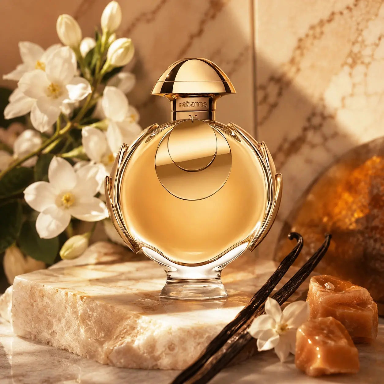 Rabanne Olympea Elixir EDP Intense 50ml in a soft pastel luxury scene with warm golden tones and elegant styling.